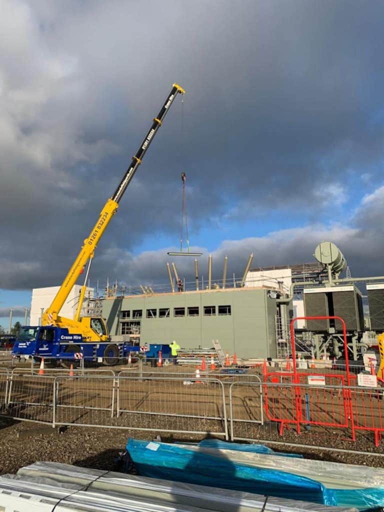 Cranes on site lifting panels into place for fixing