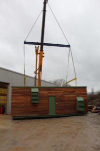 The acoustic plant room is craned out of the factory ready for loading